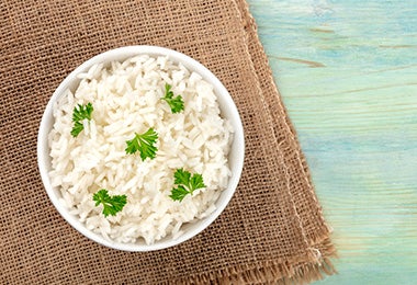 Arroz basmati en un tazón con hojitas de cilantro sobre un mantel café