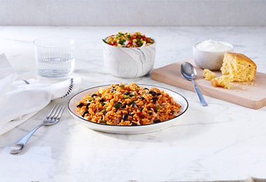 Tipo de arroz con frijoles, arvejas y tomate acompañado de un vaso de agua y ensalada