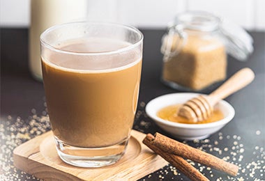 Bebida caliente con leche, café, miel y azúcar morena sobre una superficie negra.