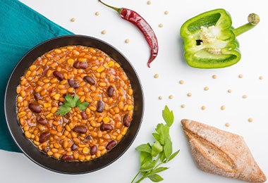 Plato de frijoles, sobre una mesa con chile y pimentón