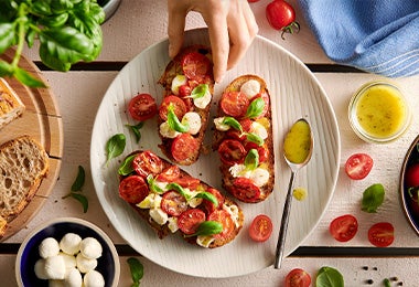 Ensalada caprese con aceite de oliva y un par de hojas de albahaca en toma cenital