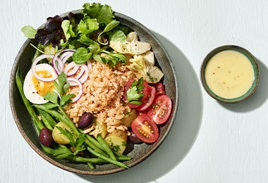 Ensalada Nicoise en bowl, con huevo duro, tomates, aceitunas y papas