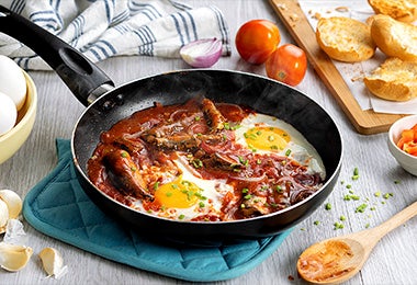 Huevos shakshuka con perejil, carne y salsa en una sartén