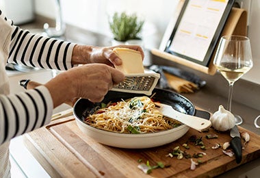 Mujer rallando queso parmesano en receta de pasta  