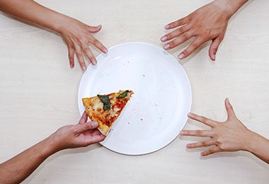 Plato con pizza y manos para calcular porciones de alimentos  