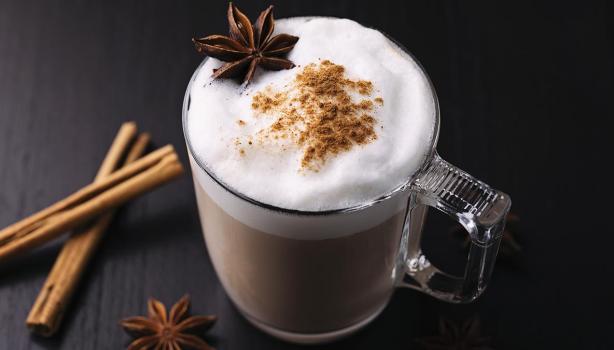 Bebida caliente con leche, canela y anís en una taza de vidrio grueso en una toma en picado