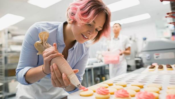 Mujer agrega relleno a galletas con manga pastelera