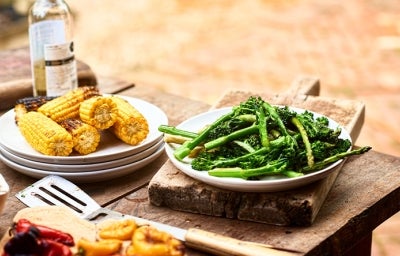 Choclos y espárragos en un asado vegetariano Choclos y espárragos sobre una mesa de madera en un asado vegetariano