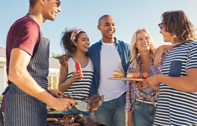 Cocinar al aire libre, la oportunidad de comer y compartir. Grupo de amigos cocinando al aire libre carne y hamburguesas a la parrilla.
