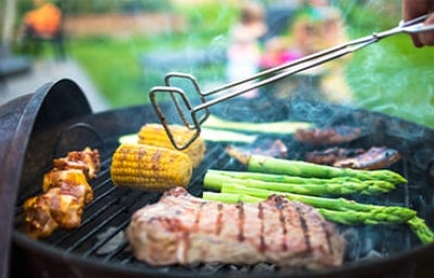 Parrilla volcánica, utensilio que aporta al sabor de las preparaciones. Filete de carne asada con choclo, chorizo y vegetales sobre parrilla volcánica.