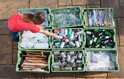 Tipos de residuos, fundamental identificarlos. Niña separando adecuadamente los distintos tipos de residuos en cajas.