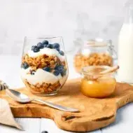 Desayuno saludable para alimentarse bien dentro y fuera de casa. Granola con yogurt griego y miel para alimentarse saludablemente.