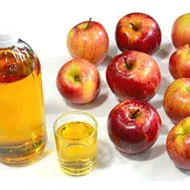 El vinagre de sidra de manzana puede ser un ingrediente mucho más útil de lo que te imaginas, descubramos sus utilidades. Vinagre de sidra de manzana al lado de manzanas.